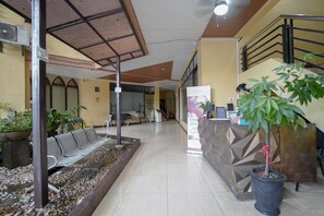 A reception area with a waiting area, a reception desk, and a staircase. - Reddoorz Arzo Hotel And Resorts (Manila)
