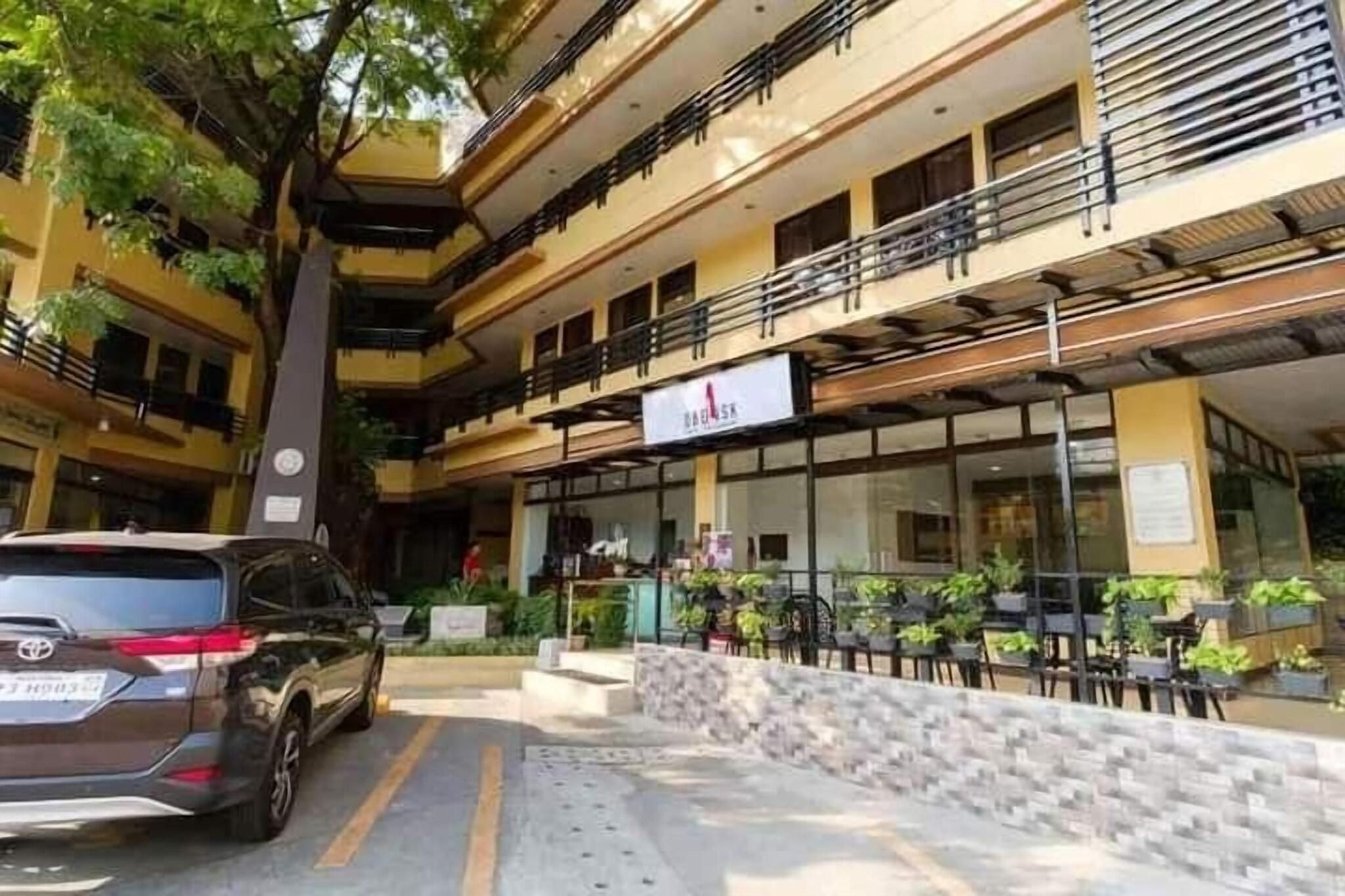 A multi-story building with a restaurant on the ground floor, outdoor seating, and a parked car.