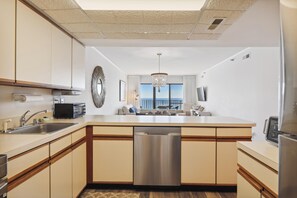 A modern kitchen with a central island, stainless steel appliances, and a view to the outside. - FREE DAILY ACTIVITIES! LINENS INCLUDED*!  The PLAZA. Direct Oceanfront 2BR/2BA condo with semi-private den that can be closed off. (Ocean City)