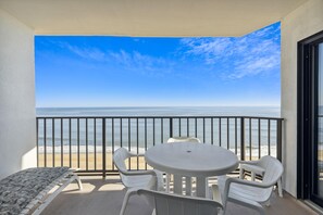 Un balcon avec vue sur l’océan, une table ronde et deux chaises.