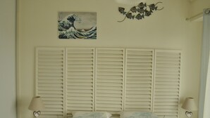 A bedroom with a large bed, white shutters, two bedside lamps, and a wall-mounted artwork. - La Rochelle T2 35m2 Avec Terrasse Dans Résidence de Standing (La Rochelle)