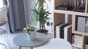 A living room with a round table, two potted plants, a bookshelf, and a grey sofa. - La Rochelle T2 35m2 Avec Terrasse Dans Résidence de Standing (La Rochelle)