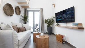 Moderni olohuone, jossa on sohva, sohvapöytä ja seinälle asennettu televisio.