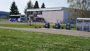 En moderne bygning med fladt tag og store vinduer, omgivet af en græsplæne med hvide blomster.