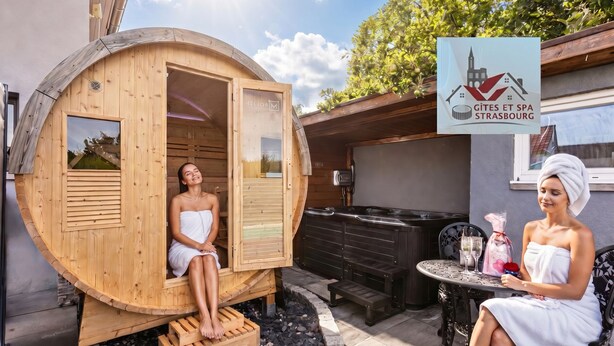 Una sauna in legno con la porta aperta, un tavolo con una bottiglia e un bicchiere, e un cartello con un logo.