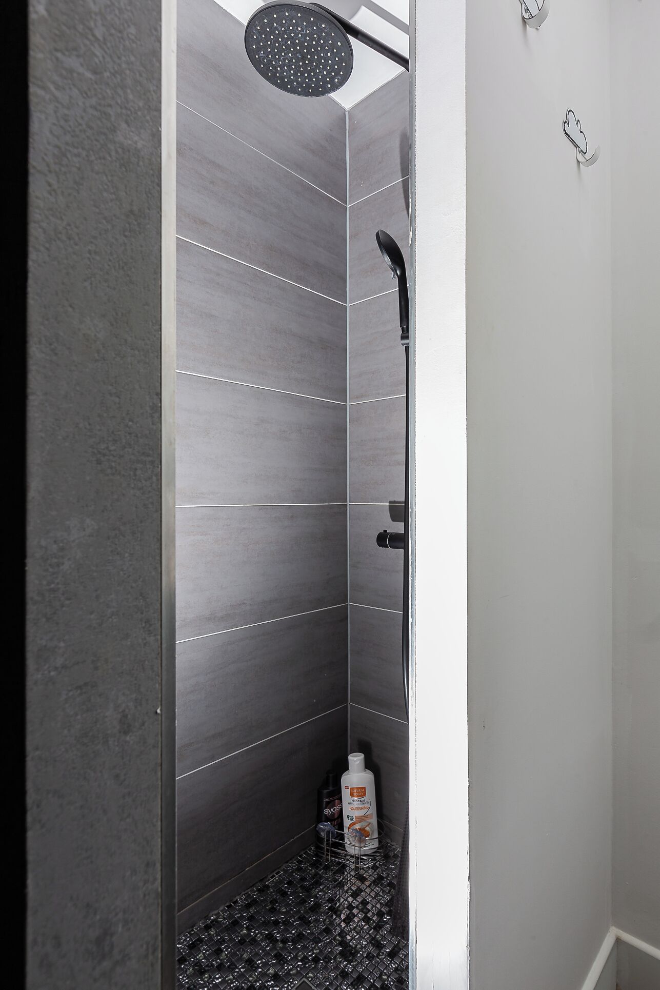 A modern shower with a rain showerhead, a handheld showerhead, and a handheld massager.