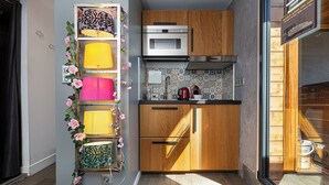 Una cucina compatta con mobili in legno, un forno a microonde e uno schienale piastrellato.