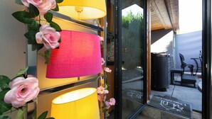 Ingresso con porta in vetro, parete gialla, paralumi rosa e rose rosa.