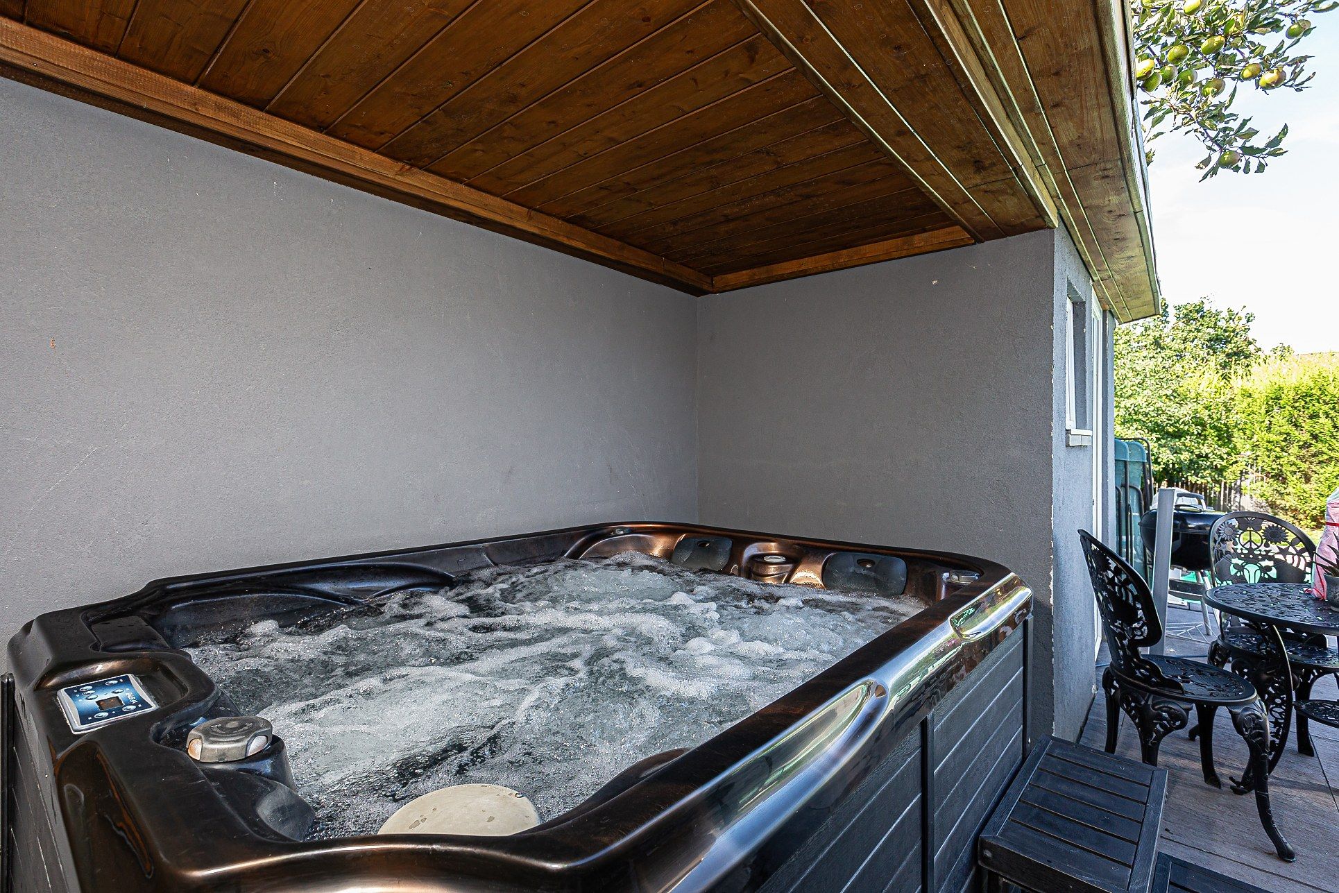 A hot tub with a wooden ceiling and a patio area with outdoor furniture.