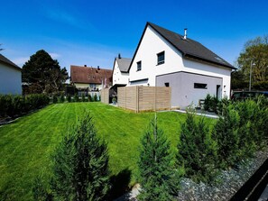 A modern two-story house with a well-maintained lawn and a wooden fence. - Villa 250m² with private spa, barbecue, table football (Hurtigheim)