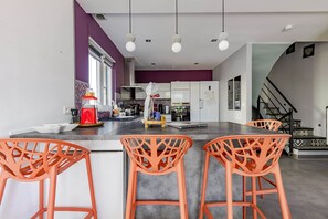 A modern kitchen with a central island, bar stools, and a staircase leading to an upper level. - Villa 250m² with private spa, barbecue, table football (Hurtigheim)