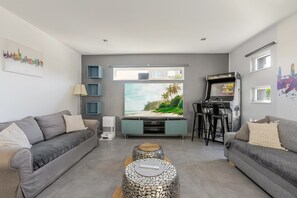 A living room with grey sofas, a flat-screen TV, a gaming console, and a large window with a beach view. - Villa 250m² with private spa, barbecue, table football (Hurtigheim)