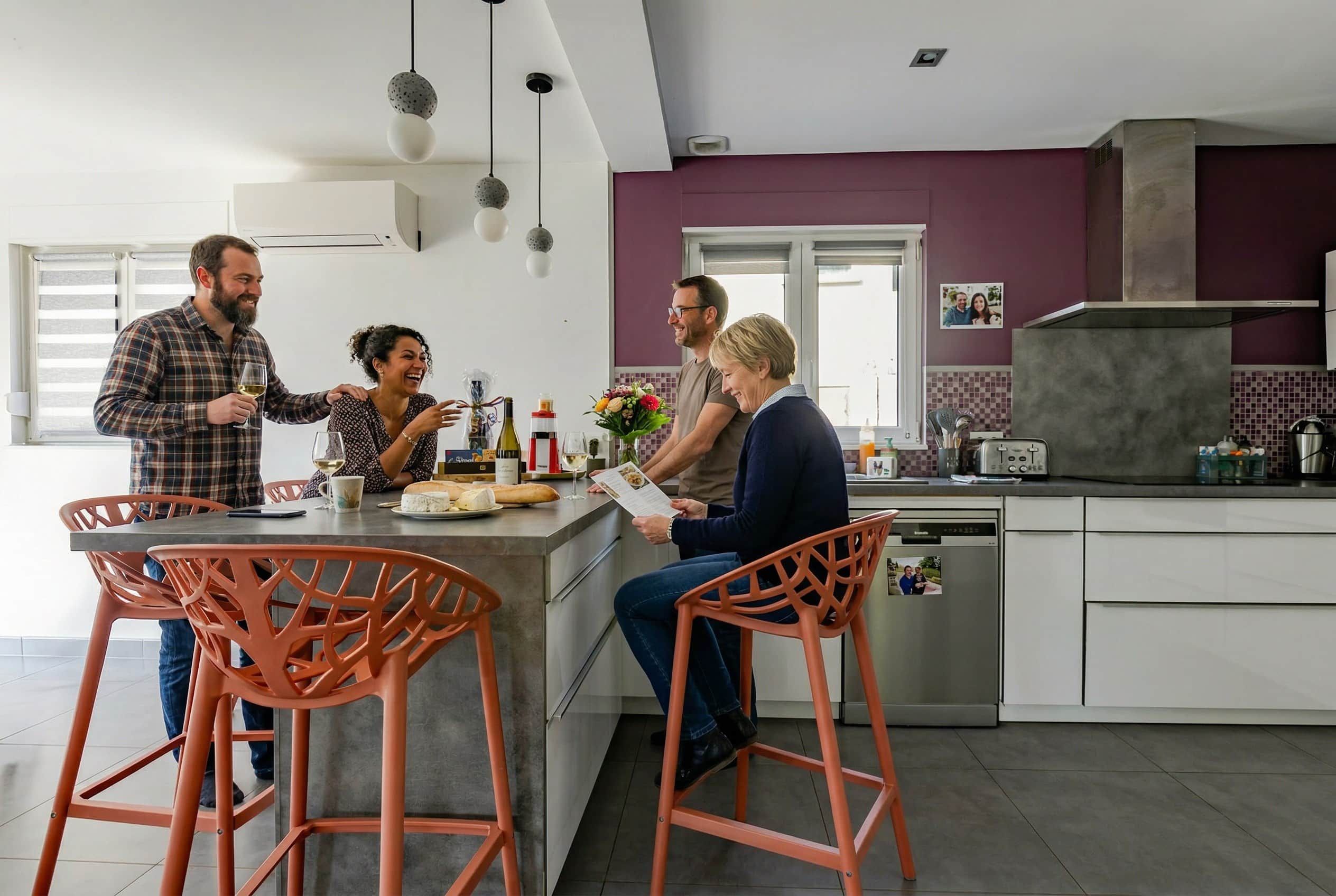 A modern kitchen with a central island, bar stools, and a dining area with a window.