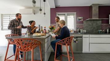 A modern kitchen with a central island, bar stools, and a dining area with a window.