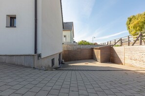 A paved outdoor area with a wooden fence, a small window, and a building in the background. - Villa 250m² with private spa, barbecue, table football (Hurtigheim)