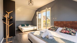 Une chambre à coucher comprenant un lit, un banc, un porte-manteau et une porte-fenêtre coulissante donnant sur un espace extérieur.
