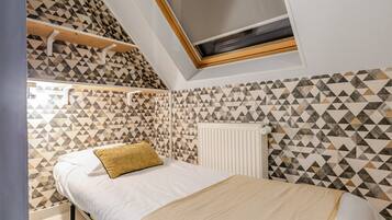 A bedroom with a bed, a radiator, and a geometric patterned wall.