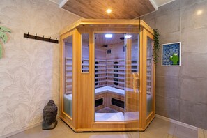 Una sauna angolare con rivestimento in legno, porte in vetro e un pannello di controllo interno.