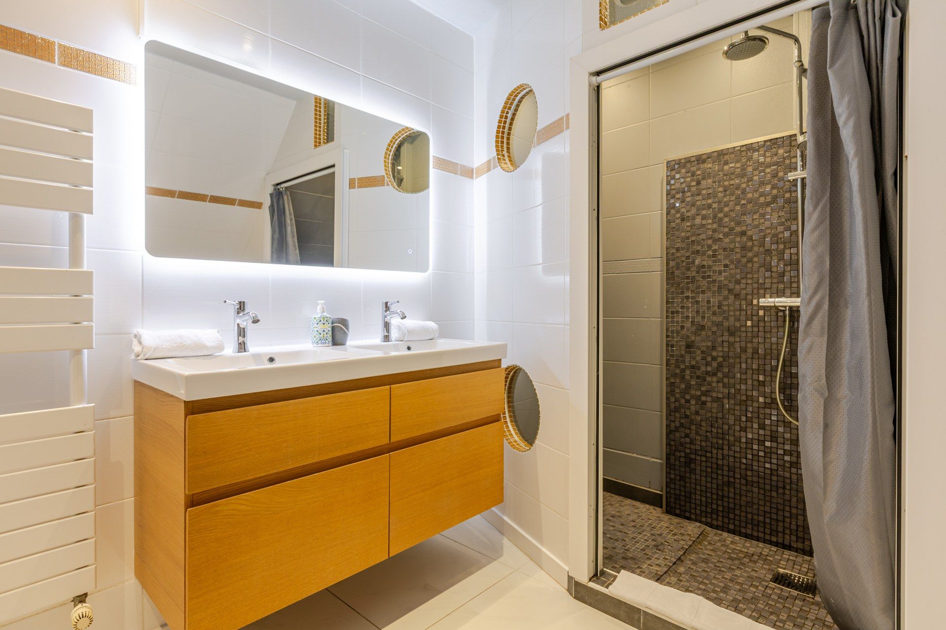Une salle de bain moderne avec un meuble-lavabo, un grand miroir et un espace douche.