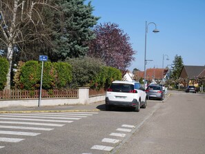 A residential street with parked cars, a pedestrian crossing, and a sign indicating 'Rue des Vergers.'