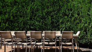 A patio with six beige chairs and tables, set against a backdrop of dense green foliage. - Villa 180m² with private spa, barbecue, table football (Ittenheim)