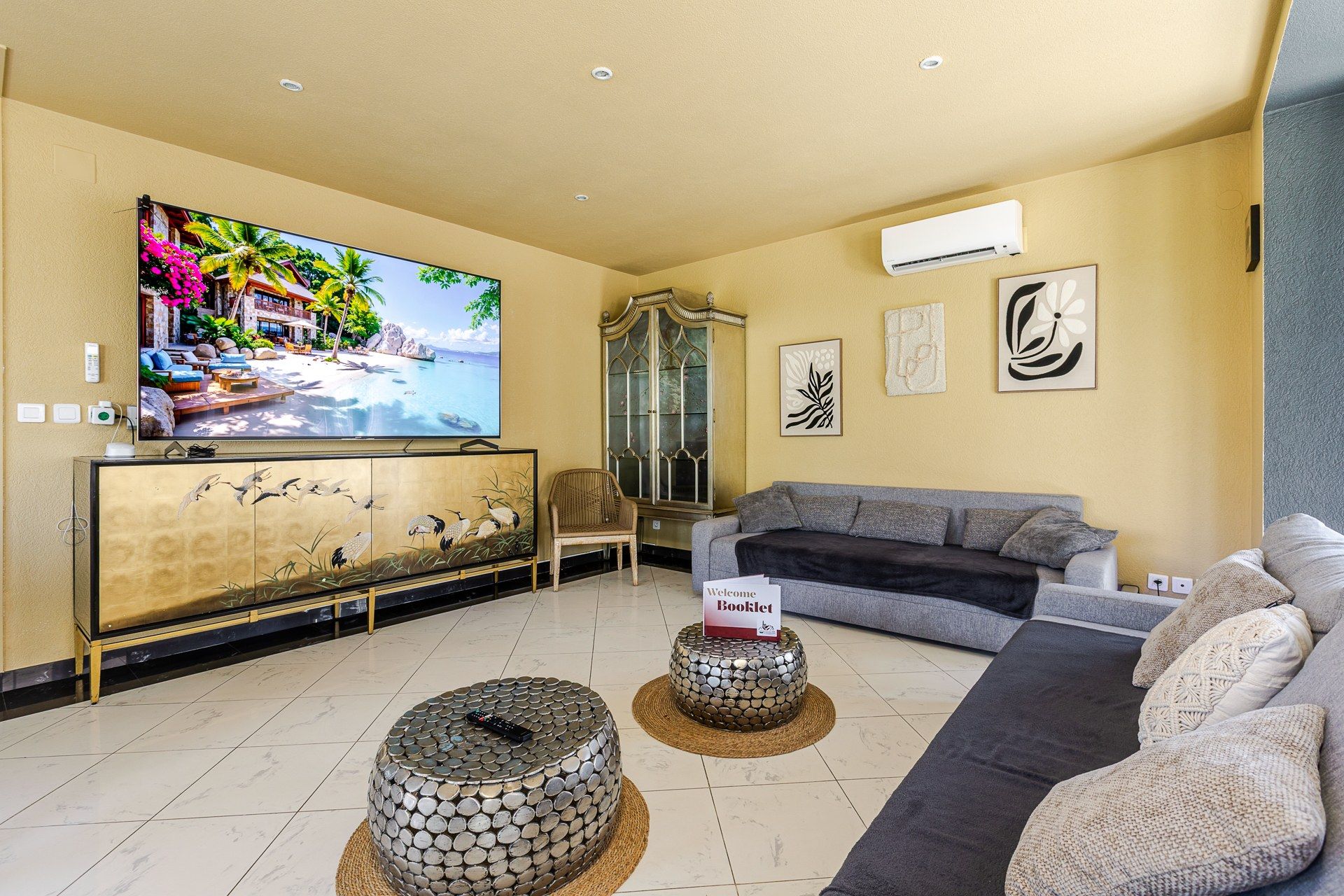Un salon comprenant un téléviseur, un canapé, un meuble décoratif et une table basse ronde originale.