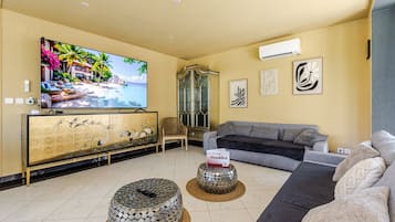 Un salon comprenant un téléviseur, un canapé, un meuble décoratif et une table basse ronde originale.
