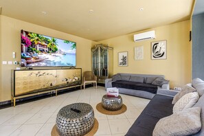 A living room with a television, sofa, decorative cabinet, and a unique round coffee table.