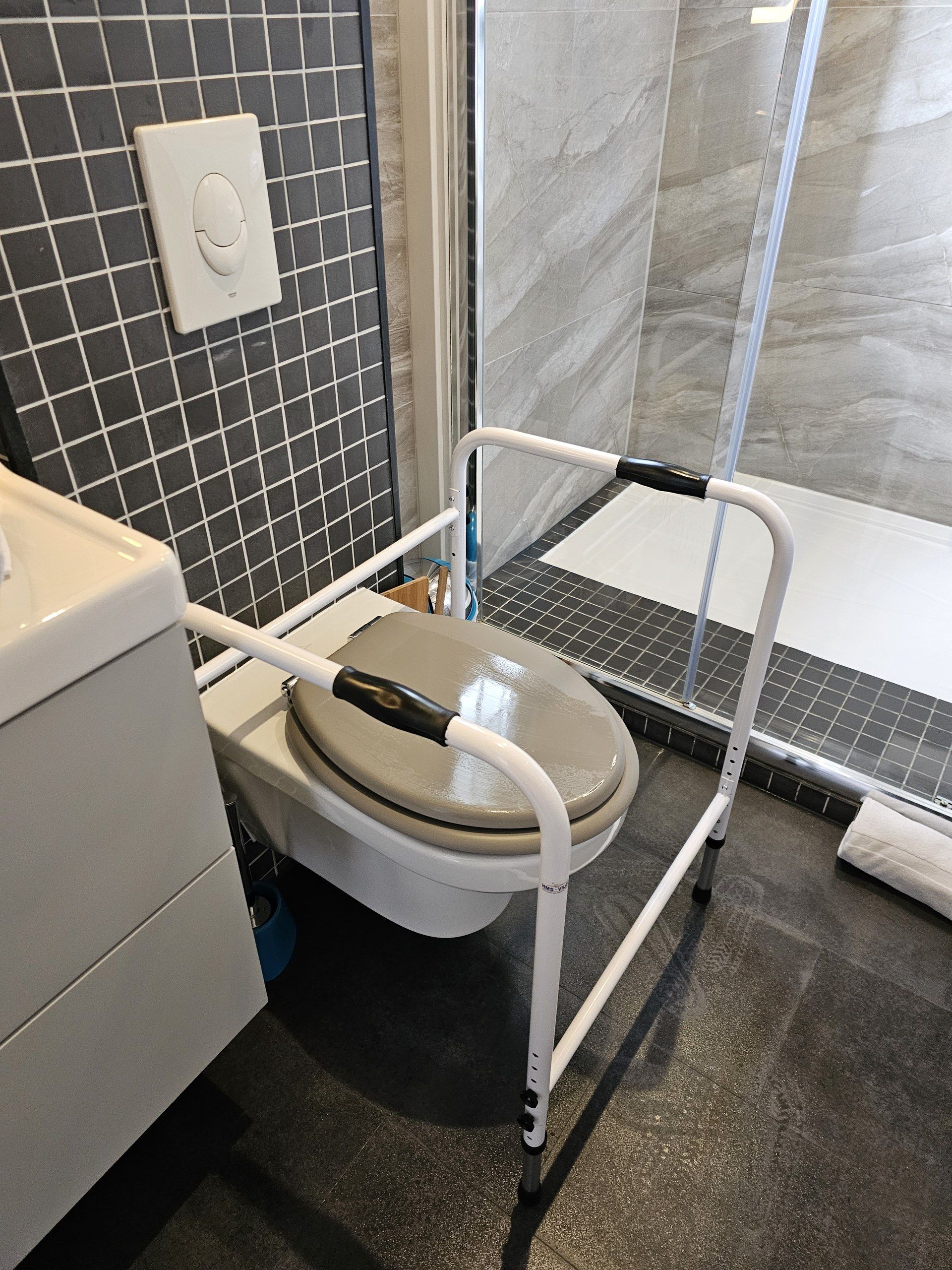 A bathroom with a toilet, a shower, and a tiled floor.