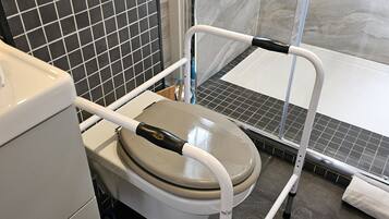 A bathroom with a toilet, a shower, and a tiled floor.