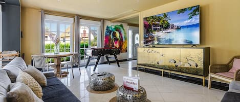Un hall de hotel con un sofá, una mesa, sillas, un televisor y un cuadro.