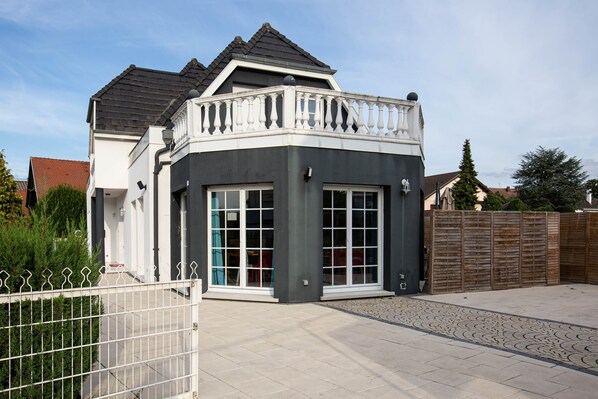 A modern house with a grey facade, a balcony with white balustrades, and a gated entrance. - Villa Ours – Private spa, games room, 15 guests (Ittenheim)