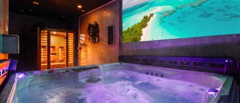 A hot tub with a view of a beach and a tropical mural on the wall.