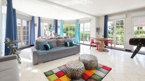 A spacious living room with a grey sofa, two ottomans, a colorful rug, and a pool table. - Villa 200m² with private spa, barbecue, table football (Ittenheim)