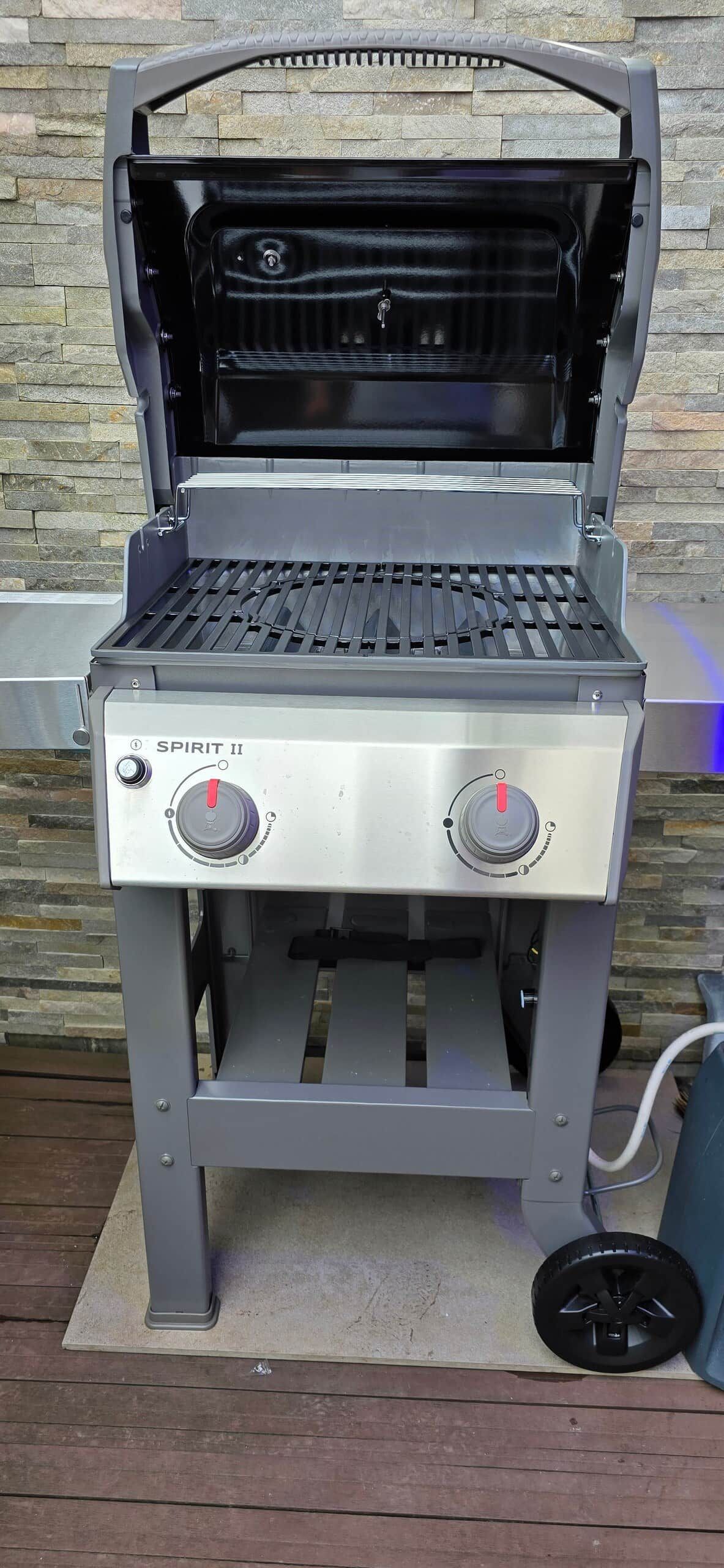 Ein Gasgrill mit zwei Reglern, einem Klappdeckel und einem Metallrost.