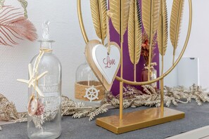 A decorative display with a glass bottle, a heart-shaped ornament with 'Love' written on it, and golden feather-like decorations. - Gites Spa Strasbourg Appartement le 14 jacuzzi sauna privé, Gite le 14 (Furdenheim)