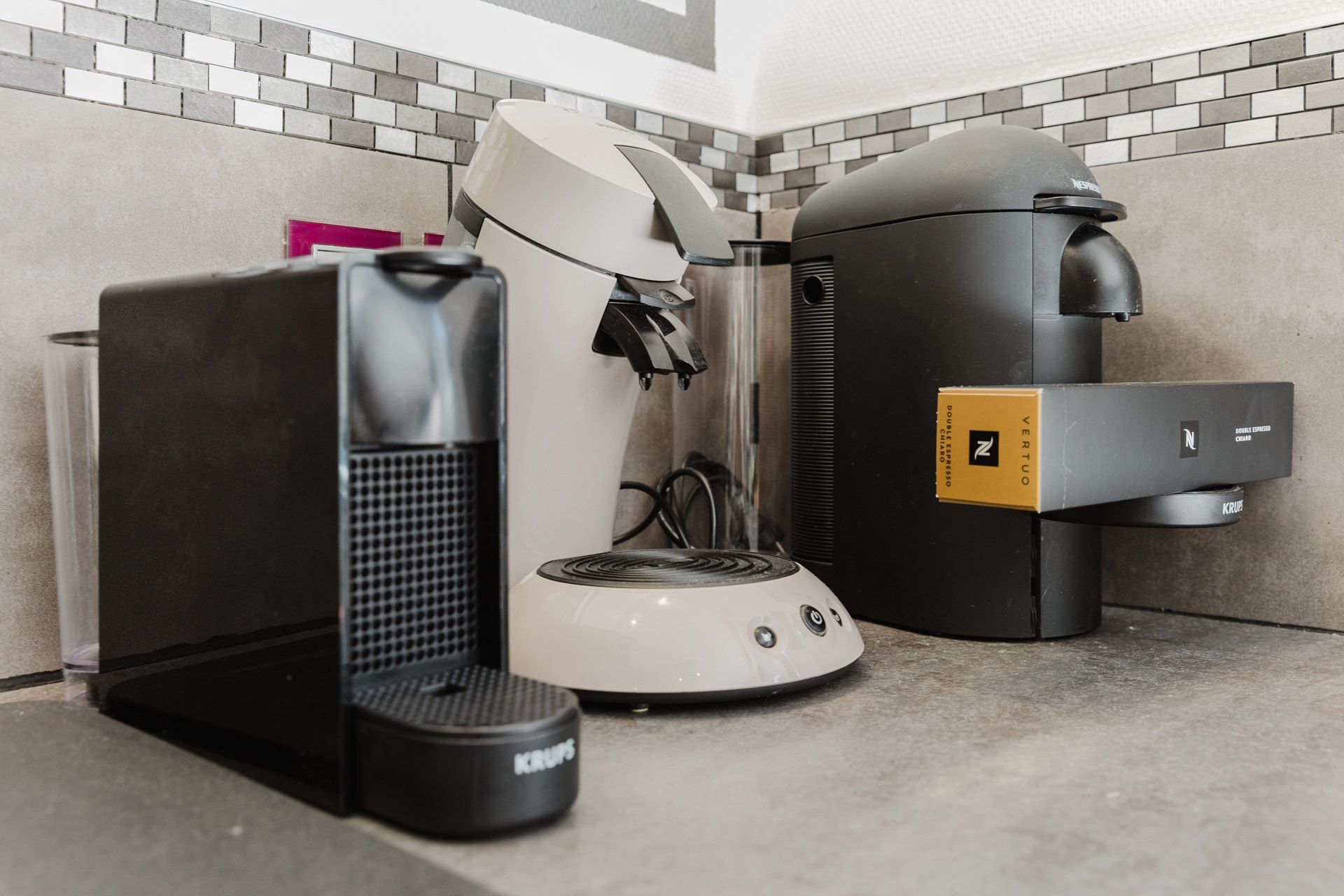 Eine Kaffeemaschine, ein Wasserkocher und ein Mülleimer auf einer Arbeitsplatte.