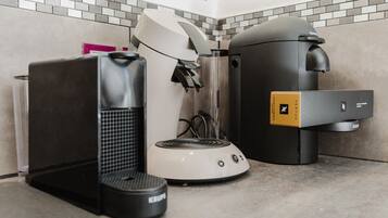Eine Kaffeemaschine, ein Wasserkocher und ein Mülleimer auf einer Arbeitsplatte.