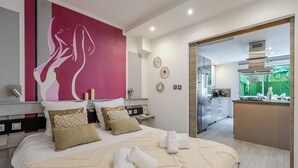 Een moderne hotelkamer met een groot bed, een kitchenette en uitzicht op een groene tuin.