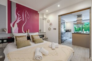 Habitación de hotel moderna con una cama grande, un cuadro en la pared y vistas a la cocina y al jardín.