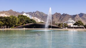 A waterfront park with a fountain, a modern building, and mountains in the background. - CHAYOFA SUITES - STUDIO (Santa Cruz de Tenerife)