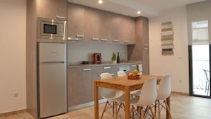 A modern kitchen with a built-in microwave, a refrigerator, and a dining area with a wooden table and white chairs. - 1.2 NEW in center ROSES with WI-FI, AC and TV sat at 60 m MAR (Roses)