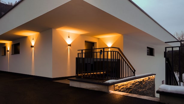 A modern building with a white exterior, a stone base, and a black staircase.