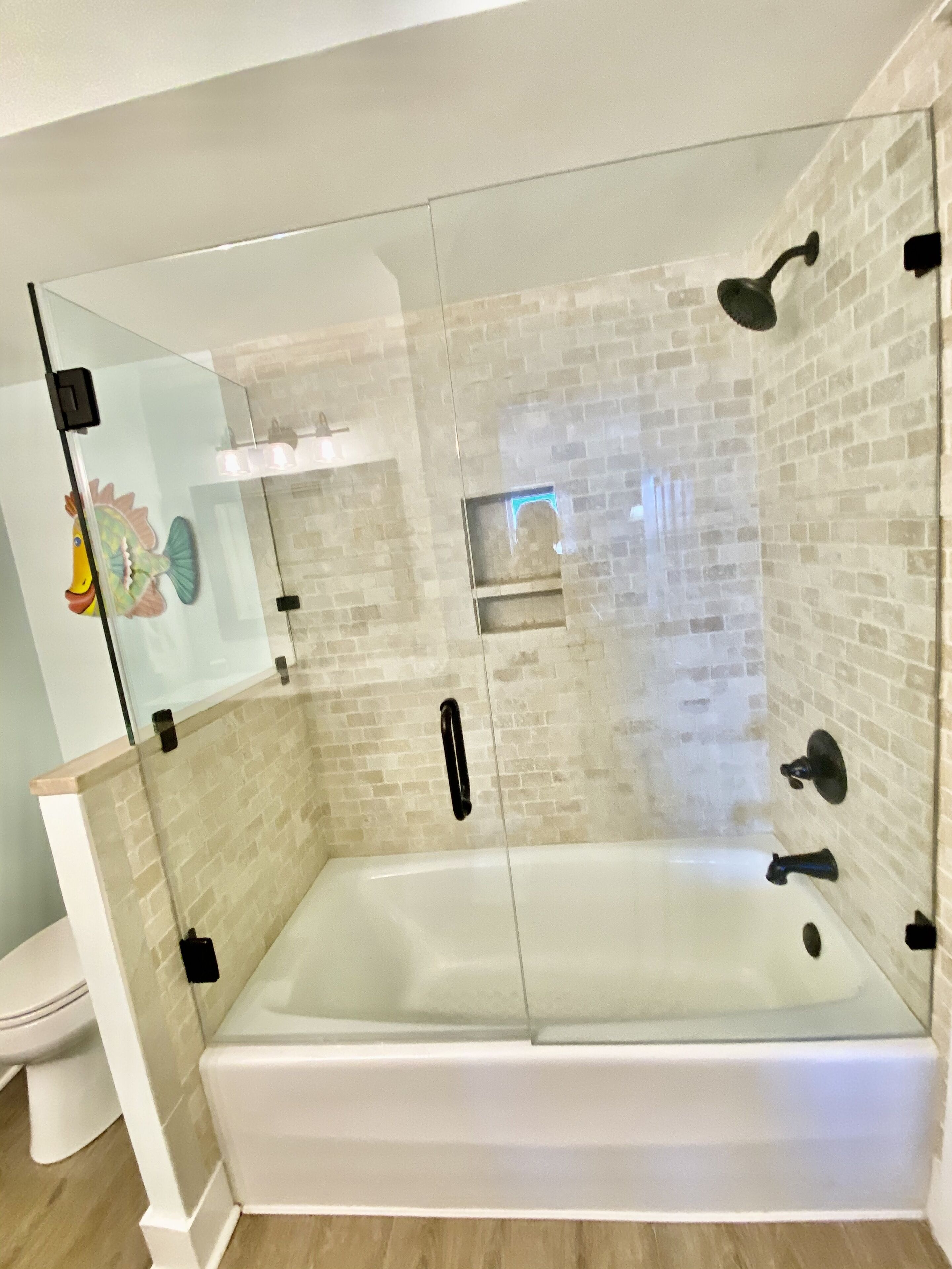 Ein modernes Badezimmer mit einer gläsernen Duschkabine, einer weißen Badewanne und einem WC.