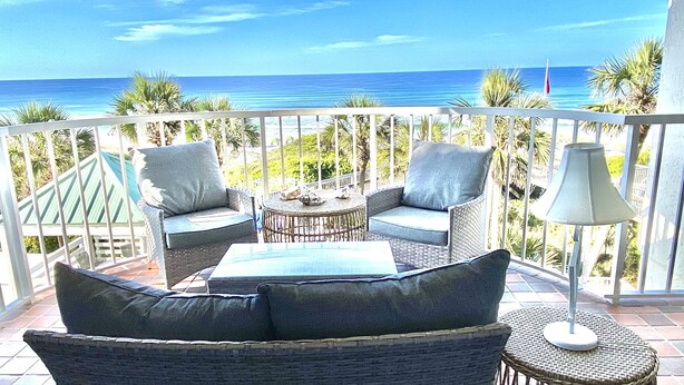 A balcony with wicker furniture, a table, and a lamp.