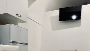 A modern kitchen with a built-in refrigerator and a flat-screen TV mounted on the wall. - Dimora Sportelli (Polignano a Mare)