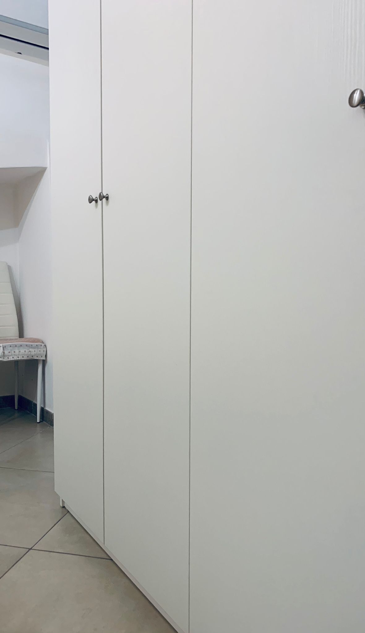 A white wardrobe with two doors and a small mirror.