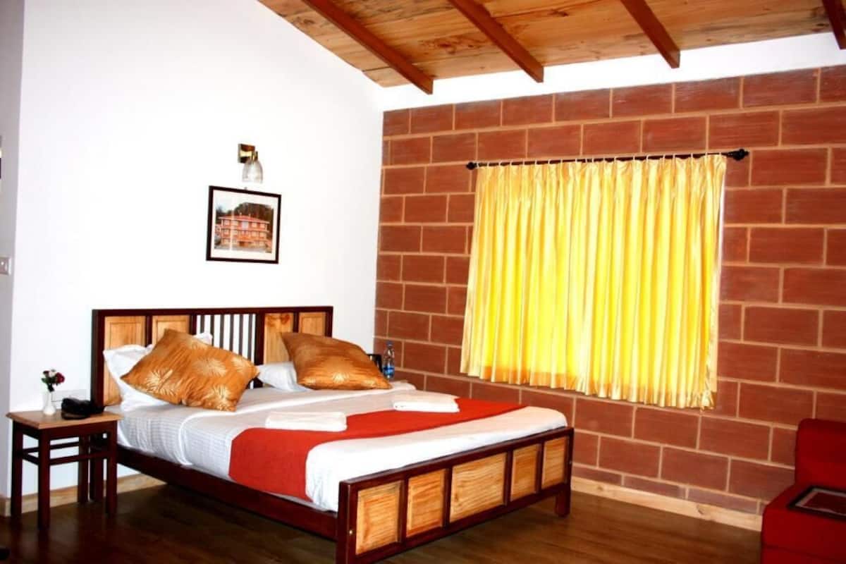 A bedroom with a wooden bed, a brick wall, and a yellow curtain.