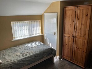 A bedroom with a bed, a window with blinds, a wardrobe, and a door. - Sweetpea Cottage - Sleeps 5, Parking & Pets Ok (Louth)