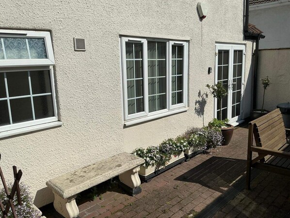 A building with a white exterior, a bench, a potted plant, and a wooden bench. - Rain Hill Cottage - Sleeps 4, Parking & Pets Ok (Louth)